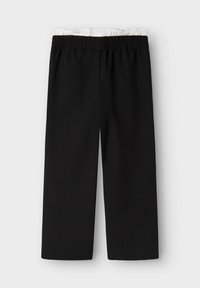 Pantalons larges noirs avec une taille élastique ; la taille a une texture intérieure blanche contrastante. Pas de motifs ou d'accents visibles.
