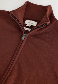 Bordó merinó gyapjú cipzáras pulóver, magas gallérral, sima textúrával és ezüst cipzárral, melyen textil címke található.