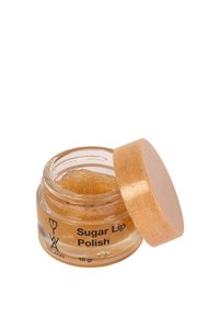 Barattolo di vetro con lati trasparenti e un coperchio dorato, contenente un gommage per labbra di zucchero di colore marrone chiaro. L'etichetta riporta "Gommage per labbra allo zucchero" e il peso.