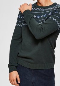 Mörkgrön stickad tröja med ett mönstrat blått och vitt design längs axlarna och halsringningen, med ribbade ärmslut och nederkant.