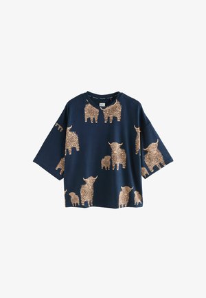 Navy blue oversized t-shirt featuring a pattern of gold-brown shaggy Highland cows in various sizes. Short sleeves and round neckline.