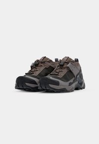 Brown and gray hiking shoes with a rugged design, textured fabric, reinforced toe caps, and adjustable lacing system. Soles are thick and patterned.