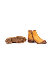 Botas de cuero hasta el tobillo en color amarillo con suela marrón, que cuentan con un cierre lateral y una suela exterior de goma texturizada para un buen agarre. Diseño con tacón.