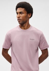 Ροζ μπλουζάκι κοντομάνικο από βαμβάκι με στρογγυλή λαιμόκοψη. Διαθέτει ένα μικρό μαύρο λογότυπο στην αριστερή περιοχή του στήθους.