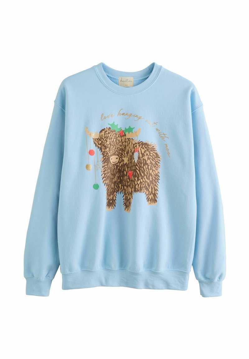 Lyseblå sweatshirt med grafik af en smilende, langhåret highland ko dekoreret med kristtorn og hængende julekugler.