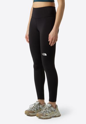 Leggings de sport noirs avec une taille haute et le logo The North Face. Associés à des chaussures de randonnée grises et beiges avec une tige en mesh.