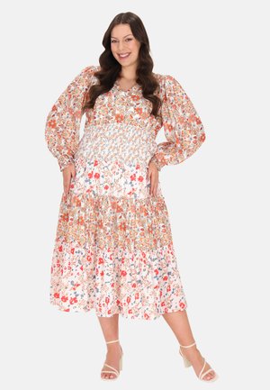 Blomster midi kjole med puffærmer, sammensyning på bodicen og lagdelt skørt i orange, pink og blå mønstre på en lys baggrund.