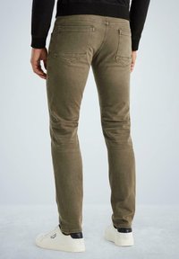 Uske slim-fit, maslinasto zelene hlače od pamuka s glatkom teksturom, pet džepova i prošivenim detaljima duž šavova, uparene s bijelim panciricama.