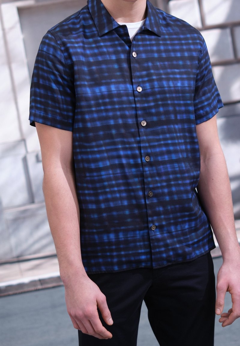 Korte mouwen shirt in donkerblauw met horizontale en verticale strepen. Gemaakt van lichtgewicht stof, met een gespreide kraag en knoopsluiting.