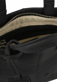 Schwarze Lederhandtasche mit einem Reißverschluss oben, beigem Stofffutter und einer kleinen Innentasche mit Reißverschluss. Robuste Trageriemen zum Tragen.