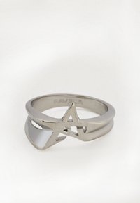 Srebrn prstan z odprtim zvezdastim dizajnom in gladkim trakom, položen na belem ozadju.