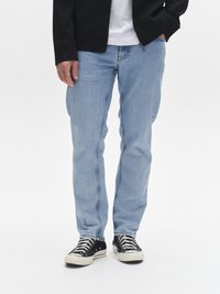 Lyseblå jeans i denim med rette ben, med synlige sømmer og sidelommer. Kombinert med svarte og hvite tøysko.