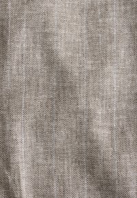 Barna texturált szövet finom halszálkamintával és enyhe fehér vékony csíkokkal, lágy, szőtt kinézetet mutatva.