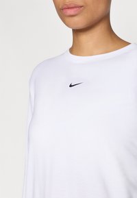 Λευκό βαμβακερό T-shirt με στρογγυλή λαιμόκοψη και ένα μικρό μαύρο λογότυπο Nike στο στήθος. Απαλή υφή, χαλαρή εφαρμογή.