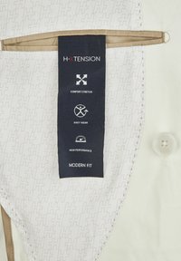 Weißes Hemd mit strukturiertem Muster und H-XTENSION-Branding. Enthält ein schwarzes Etikett mit den Aufschriften 'Comfort Stretch', 'Easy Wear' und 'High Performance'.