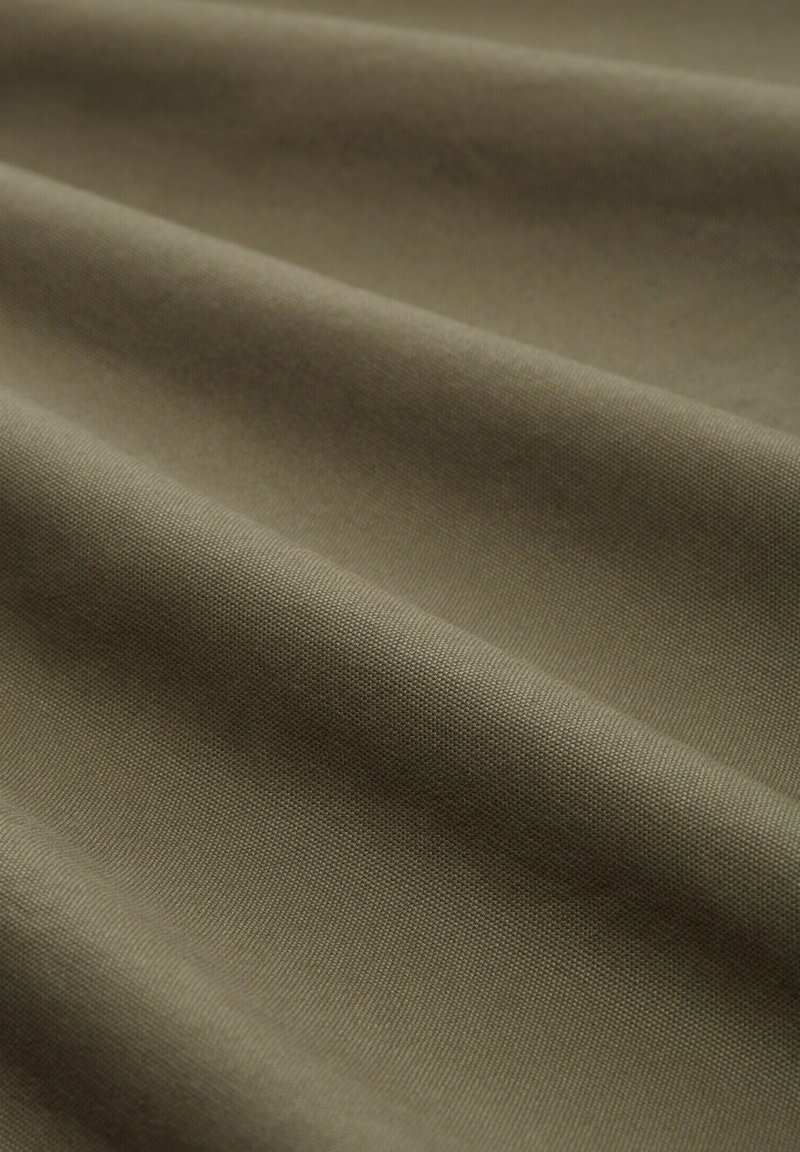 Tela verde oliva con una superficie texturizada, que presenta suaves pliegues y un patrón de tejido liso. Material ligero y versátil.