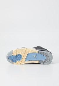 Sort sneakersål med mønstrede gummi, der har blå og grå accenter, samt et karakteristisk logo i lyseblå. Teksturerede elementer til stede.