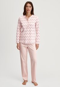Pyjama set met een lang mouwtop met een roze bloemenprint op een lichtroze achtergrond, gecombineerd met effen roze, zachte stofbroeken.