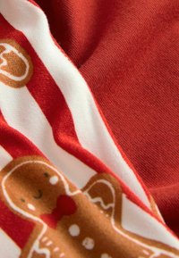 Red fabric with white stripes, featuring a gingerbread man design. The material appears soft and textured, emphasizing the playful pattern.