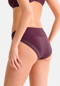 Sous-vêtements taille haute de couleur violette avec des détails en dentelle géométrique sur les côtés, présentant un tissu doux et un design offrant une couverture complète.