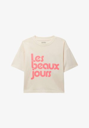 T-shirt court à manches courtes crème avec le texte rose vif "Les beaux jours" sur le devant, en police arrondie et moderne.