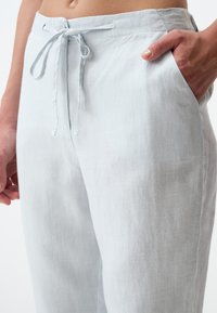 Lichtblauwe linnen broek met een ontspannen pasvorm, voorzien van een taille met trekkoord, zijzakken en een lichtgetextureerd oppervlak.