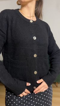 Melnas adītas kardigans ar apaļu kaklu, garām piedurknēm un sešām lielām spīdīgām pogām. Ietver divas priekšējās kabatas.