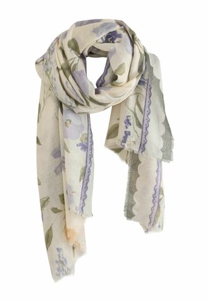 Young woman with short brown hair wearing hoop earrings, a white long-sleeve top, blue jeans, and a floral patterned scarf.