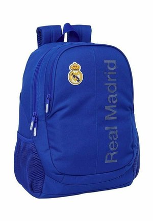Niebieski plecak z dwoma głównymi komorami na zamek, siateczkowymi kieszeniami bocznymi, logo Realu Madryt oraz napisem "Real Madrid" na przednim panelu.