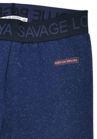 Navy blue joggers with a textured finish, featuring a black elastic waistband with "SAVAGE" and a pink "KEEP ON SMILING" tag.