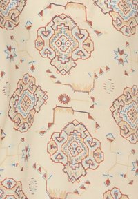 Tessuto avente motivo a pattern geometrici in rosso, blu e beige. Il tessuto ha una texture liscia con disegni intricati e piccoli accenti.