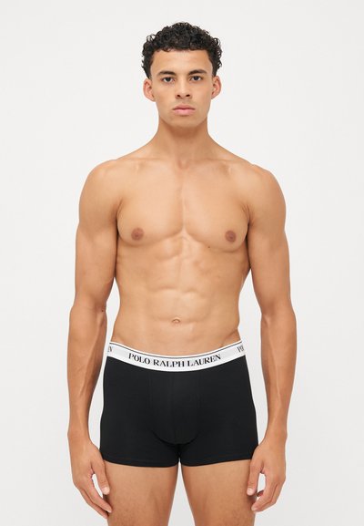 Črne bokserice z belim elastičnim pasom, na katerem je napis "POLO RALPH LAUREN". Gladek material, prilegajoča se zasnova, dolžina do sredine stegna.