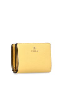 Cartera de cuero amarilla con acentos negros, que presenta un diseño compacto y rectangular, y el logo en relieve "Furla" en la parte frontal.