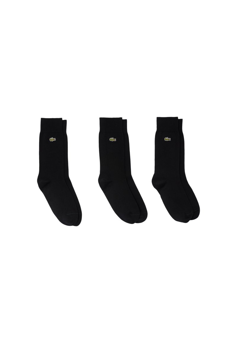 Calcetines negros con una textura suave y puños acanalados que presentan un pequeño logo verde de Lacoste en el lateral. Tres pares exhibidos en fila.