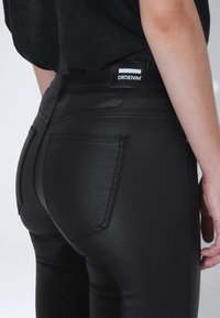 Černé džíny s vysokým pasem s lesklou texturou, zadními kapsami a štítkem "DRDENIM" na pase. Přiléhavý střih s okrasným prošitím.