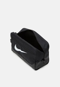 Black nylon duffle bag with a smooth texture, featuring a white Nike swoosh logo on the front, and a zippered top opening for access.