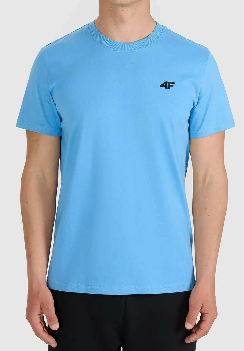 Homme portant un t-shirt uni bleu clair à manches courtes avec petit logo noir "4F" sur la poitrine gauche.