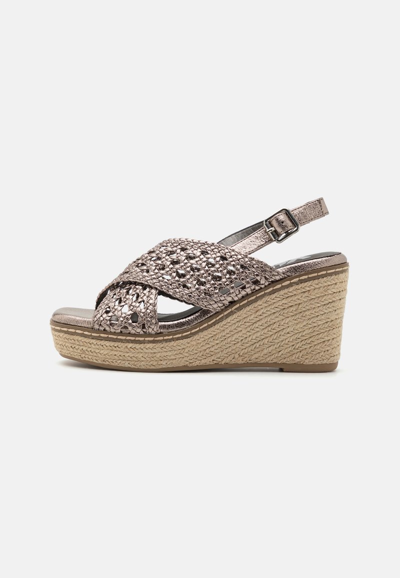 Sandalía de cuña con parte superior metálica trenzada, correa ajustable en el tobillo y plataforma similar a yute, con un acabado suave en gris plateado.