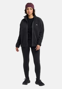 Black fleece jacket with a high collar, paired with a black top and leggings. Additions include a textured maroon knit headband and black sneakers.
