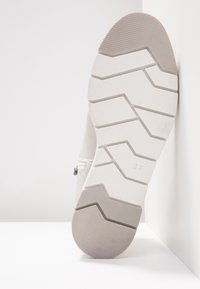 Baskets blanches avec une semelle en caoutchouc texturé présentant un motif en zigzag. Taille 37 indiquée sur la semelle. Le matériau semble doux et respirant.