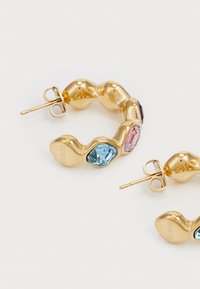 Gold hoop earrings featuring a wavy design, accented with pink and blue rectangular gemstones. Includes a post and backing for secure wear.