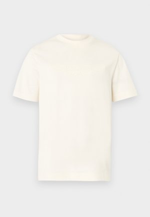 Crèmekleurig t-shirt met korte mouwen, gemaakt van zacht materiaal. Heeft een logo met textuur op de borst. Standaard ronde hals.