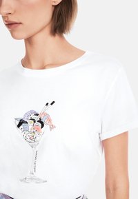 Weißes Baumwoll-T-Shirt mit einem gestickten Grafikdesign eines Cocktailglases, gefüllt mit verschiedenen Sushi-Sorten und Essstäbchen.