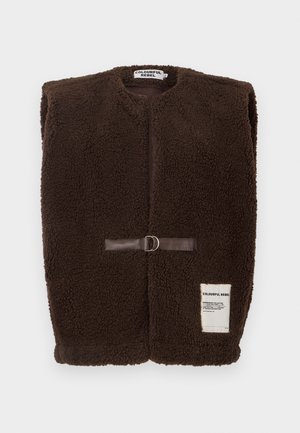 Braune Fleece-Weste mit rundem Halsausschnitt, vorderer Verschluss mit braunem Lederband und Metallring sowie einem kleinen weißen Etikett am unteren Ende.