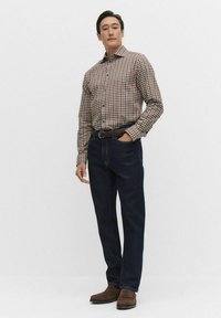 Skjorte med knapper og et flerfarvet ternet mønster, parret med mørkeblå jeans og brune ruskindsko. Casual, skræddersyet pasform.