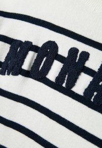 Maglione a righe con linee orizzontali bianche e blu navy. La scritta "MONA" è ben in vista in lettere in morbido filato blu navy.