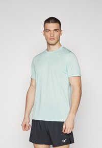 Camiseta deportiva de color azul claro hecha de una tela suave, con cuello redondo y mangas cortas. Un pequeño logo blanco está ubicado en la parte superior izquierda del pecho.