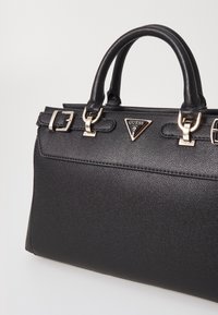 Černá syntetická kabelka s texturovaným povrchem, kovovými doplňky a strukturovaným designem. Má dvojité rukojeti a trojúhelníkové logo.