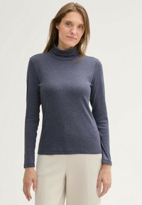 Top bleu marine à col roulé avec des manches longues, fabriqué dans un tissu doux, présentant une coupe décontractée et une texture lisse.