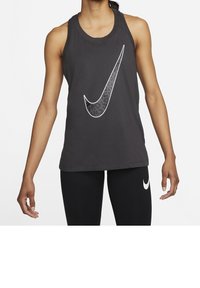 Schwarzes sportliches Tanktop mit großem weißem Nike-Swoosh-Logo; glatter Baumwollmischstoff; ärmelloses Design; kombiniert mit schwarzen Leggings.